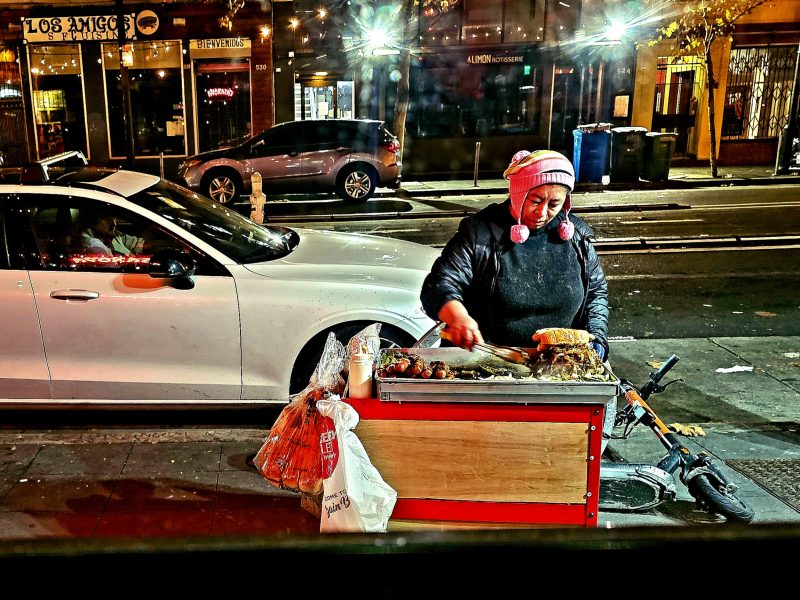 A woman is selling food on the side of the street.