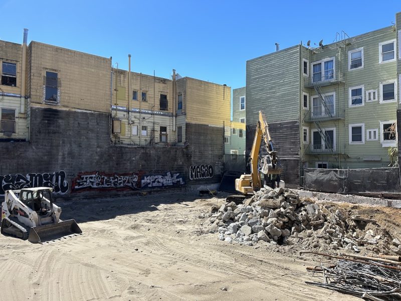 A sandy lot with one tractor and one other construction vehicle was pushing the rubble around. Former One $ store site