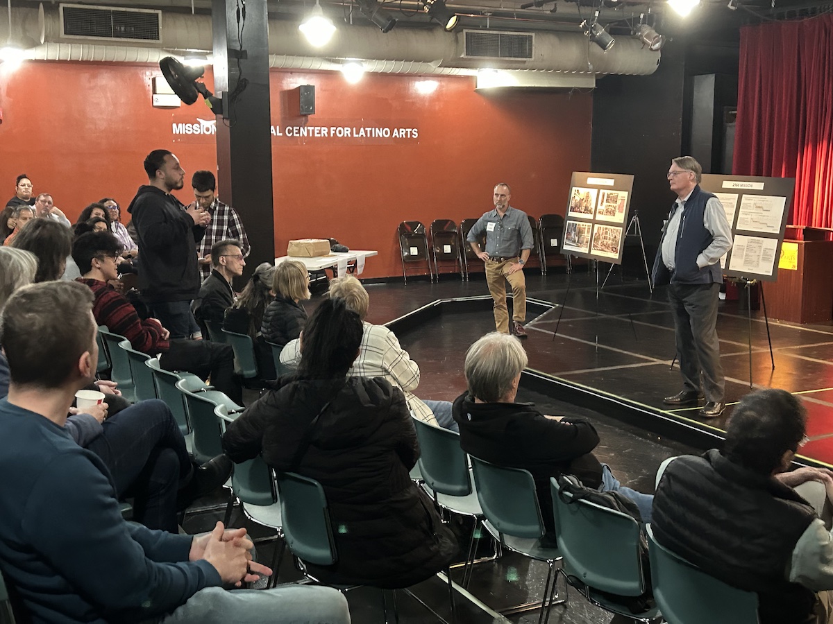 A man is speaking to a group of people in a room.