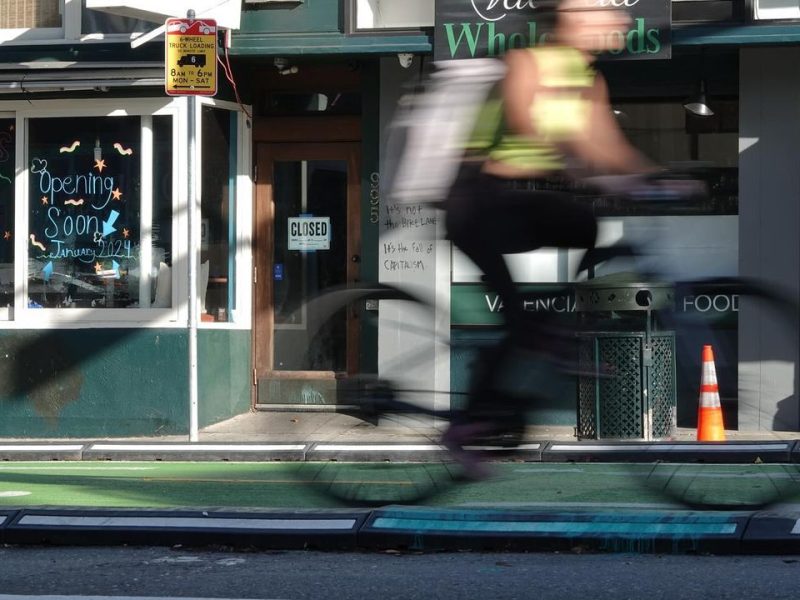 A person riding a bike in front of a store.