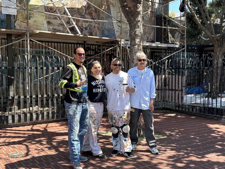 Four artists stand in front of scaffolding by the 24th St. Plaza.