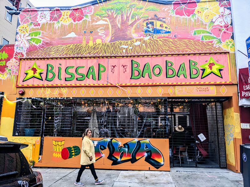 The colorful front of a store with an open porch area. bissap baobab.