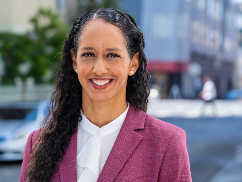 District Attorney Brooke Jenkins, a brown-skinned woman with long dark hair, wearing a purple blazer and white shirt.