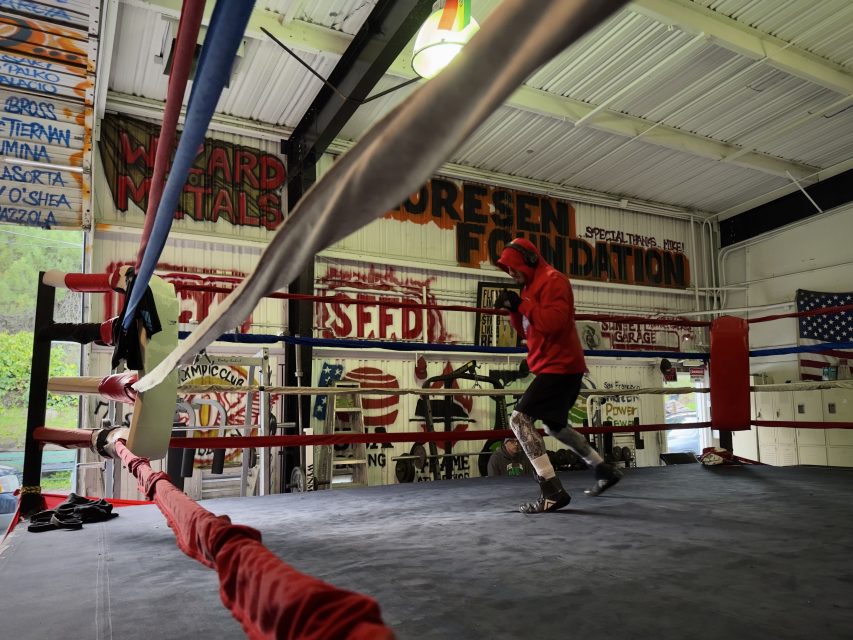 A man in a boxing ring in a gym.