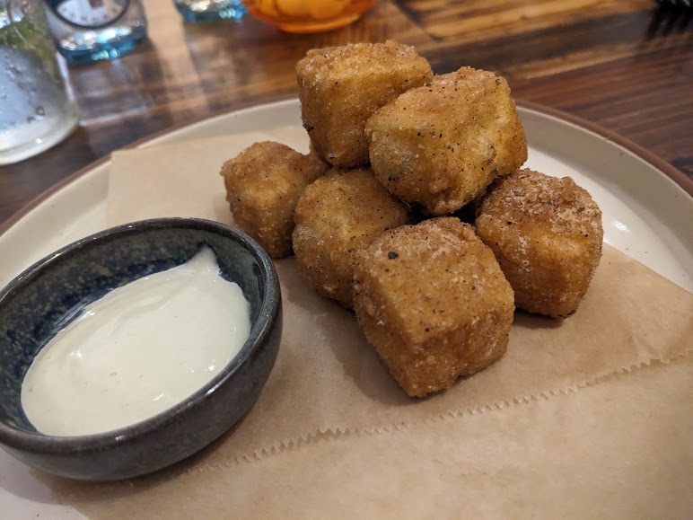 Fried tots with dipping sauce on a plate.
