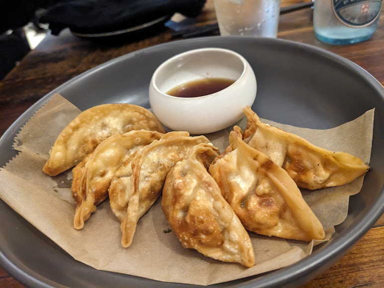 Dumplings with dipping sauce on a plate.