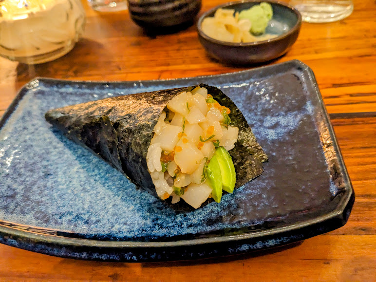 A sushi roll is sitting on a blue plate on a wooden table.