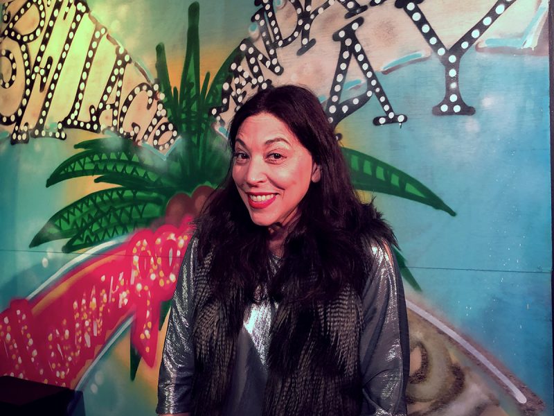 A woman standing in front of a colorful wall.