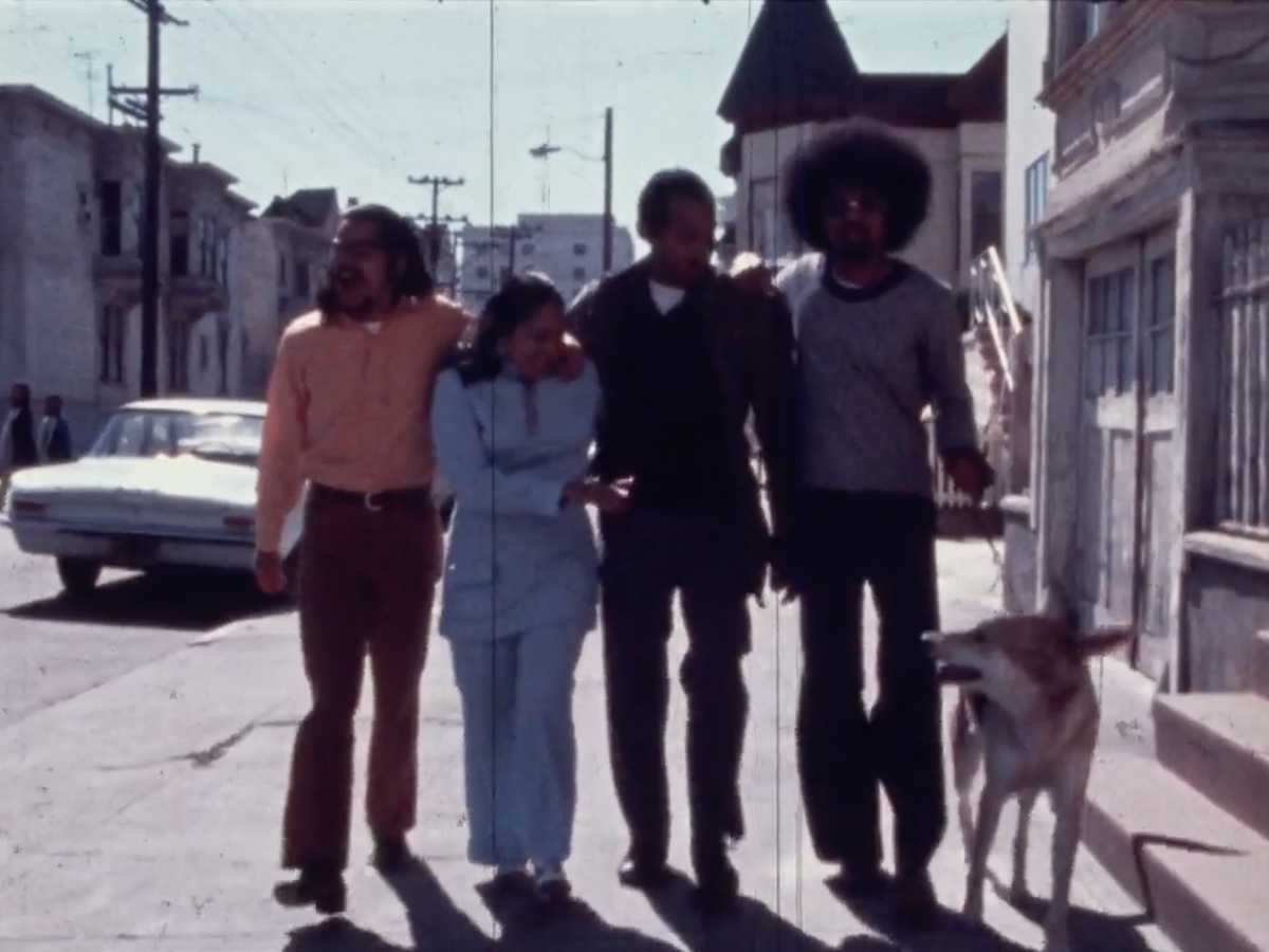 A latino family of four walking down the street with their dog.