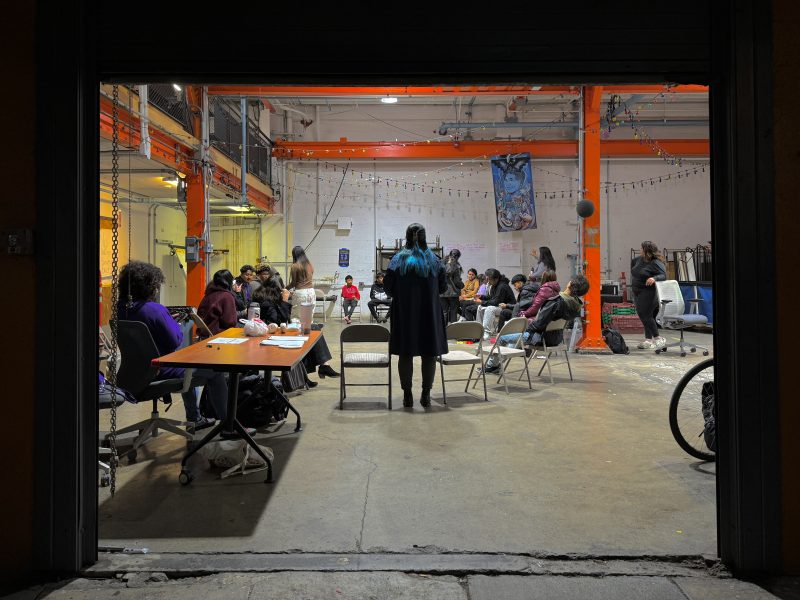 A group of people sitting at tables in a warehouse.
