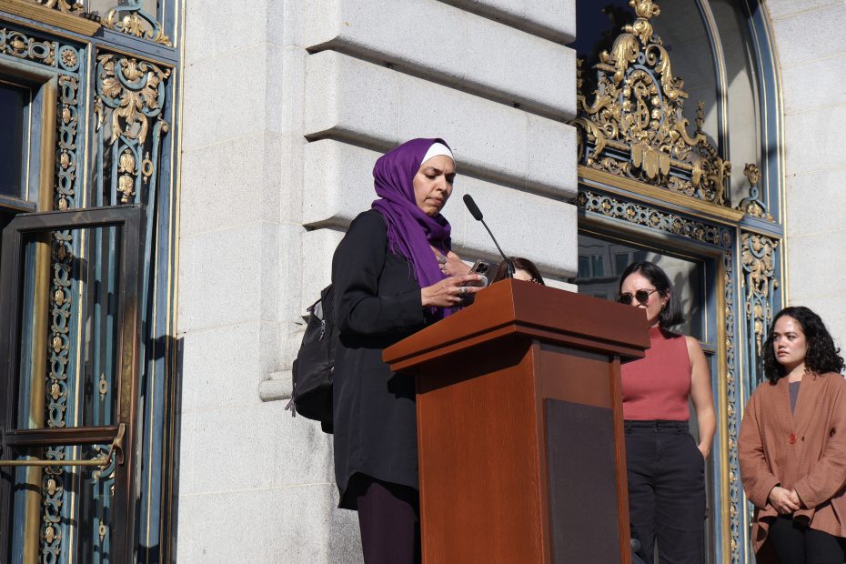 A woman in a hijab is standing at a podium.