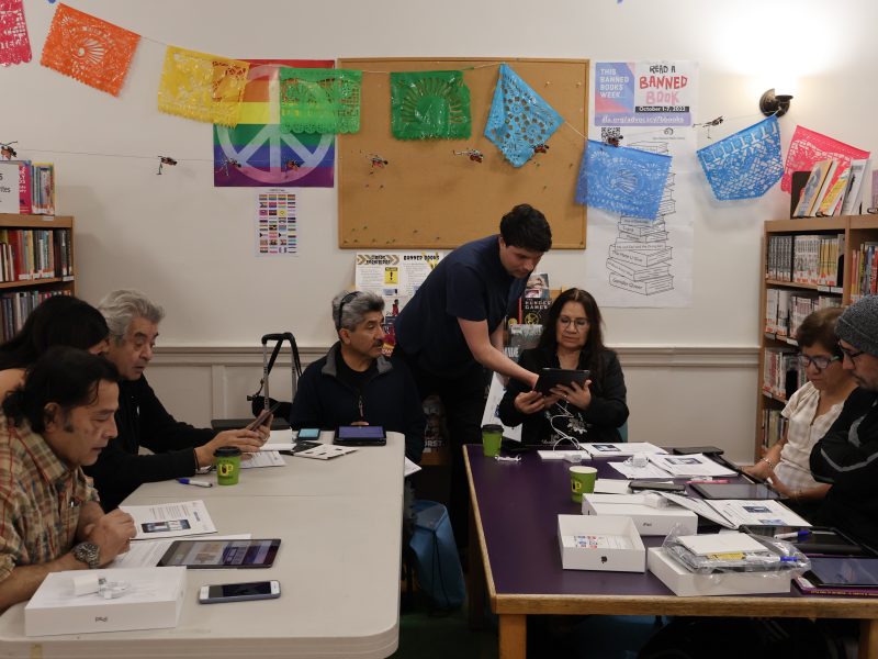 A group of people sitting around a table in a library.