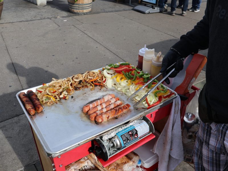 Someone grilling sausages on a mobile cart.