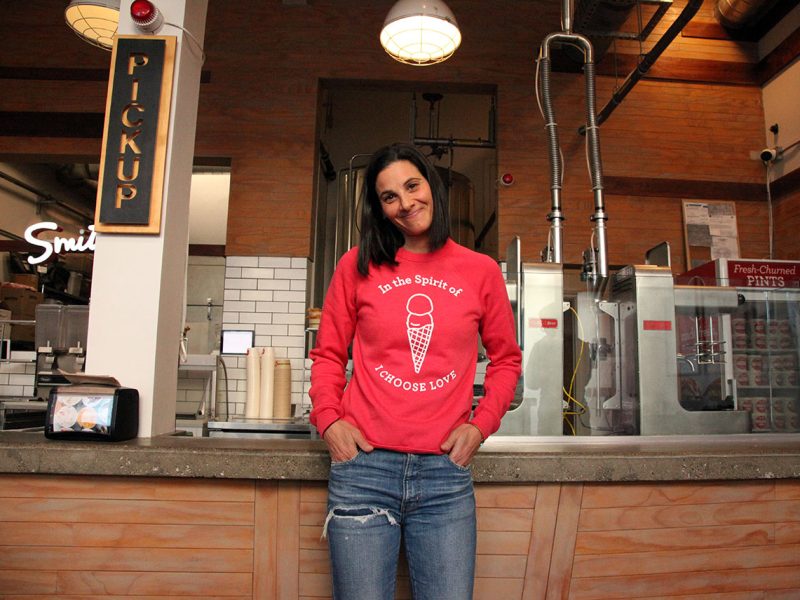 A woman in a red sweatshirt standing in front of a counter.