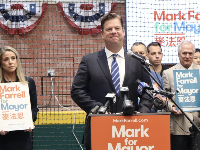 A group of people standing in front of a baseball field holding signs.