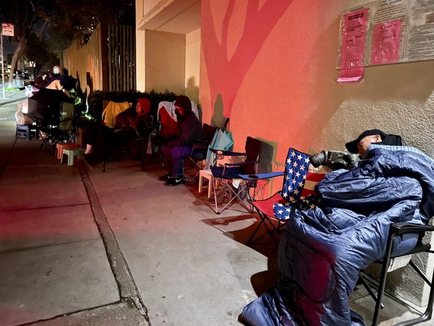 A group of people sitting on folding chairs on the side of the road