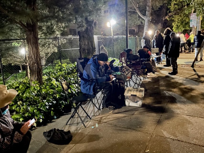 A group of people sitting on folding chairs on the side of the road