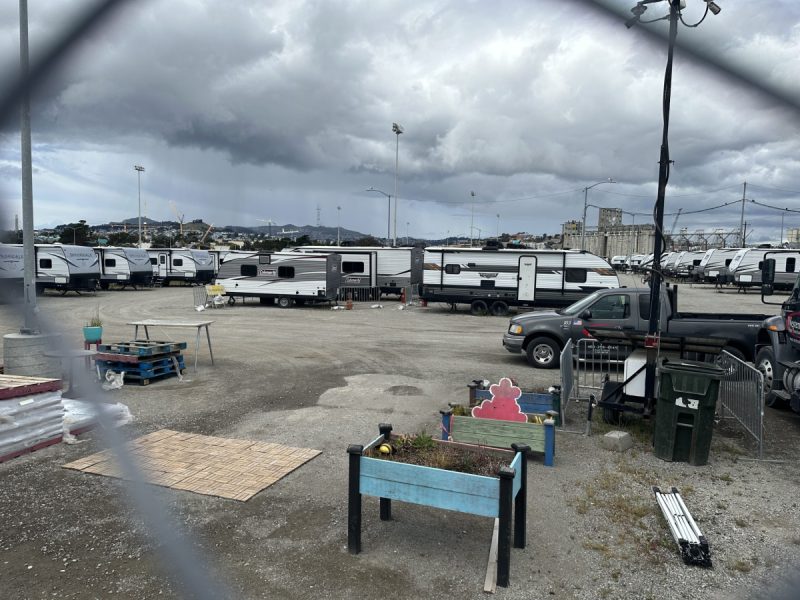 Dozens of RVs seen through a chain link fence at Pier 94
