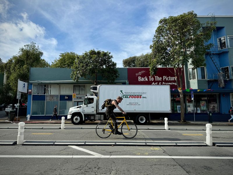 A man on a bike rides past a delivery truck in san francisco, california.