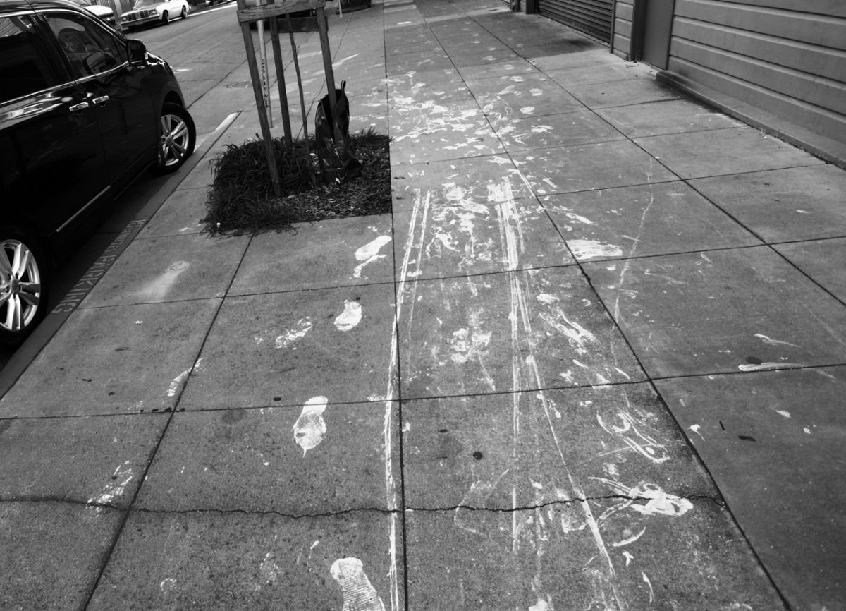 A black and white photo of a sidewalk with footprints.
