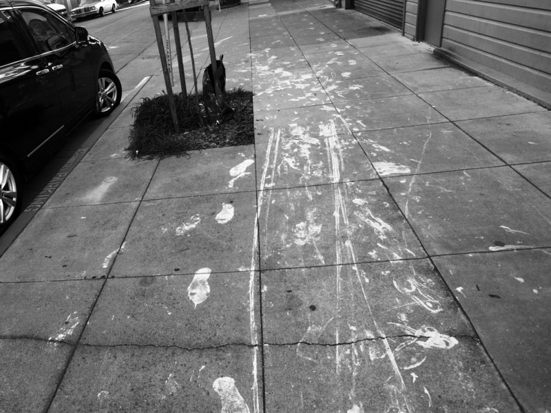 A black and white photo of a sidewalk with footprints.