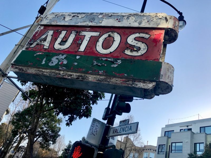 A rusty sign that says autos.