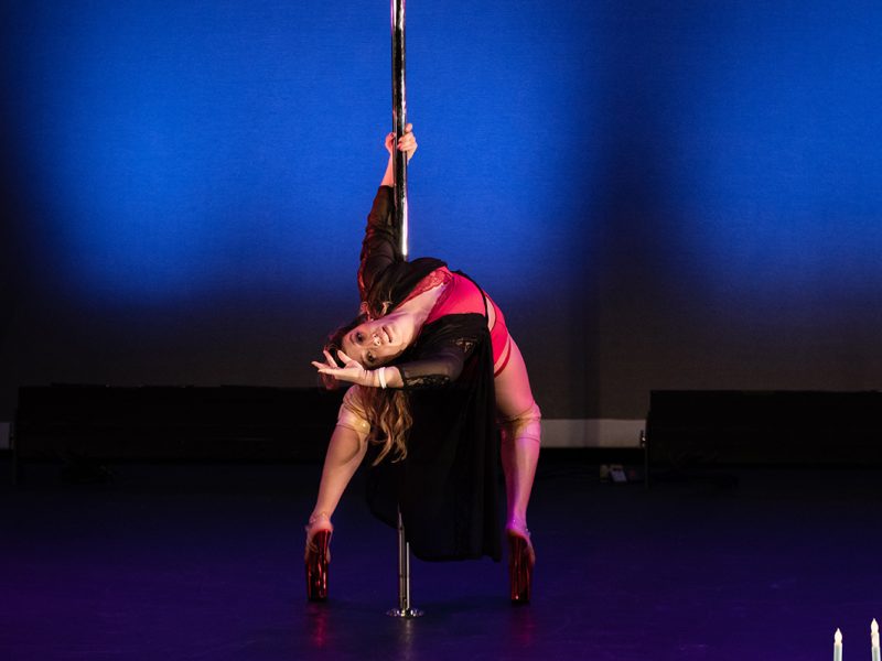 Ivy Leon, a woman, doing a pole dance on stage.