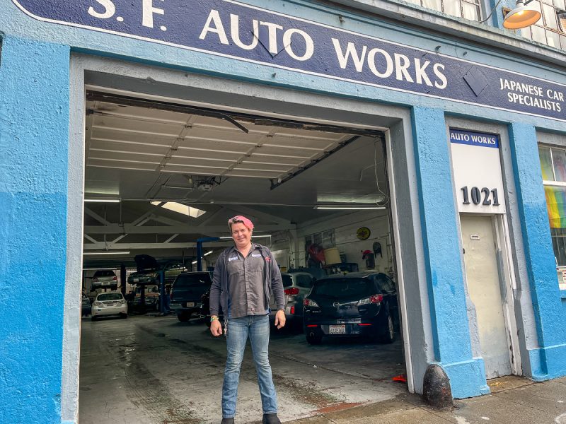 Kimberly Sawyers standing in front of her auto shop with a sign that says SF auto works.