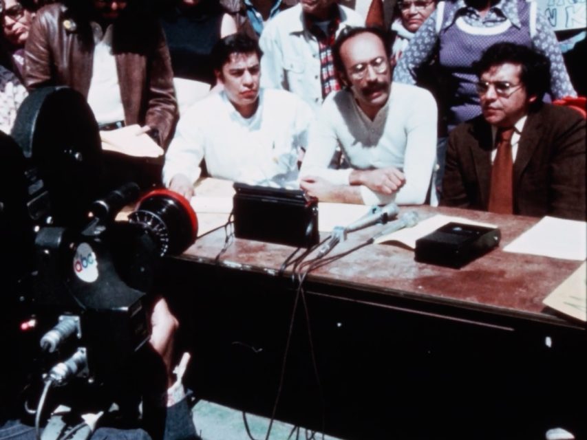 A group of people sitting at a table at a press conference.