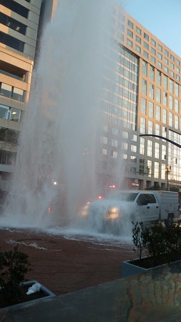 A fire hydrant is spraying water at a building.