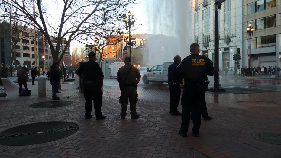 A group of police officers standing in front of a water fountain.