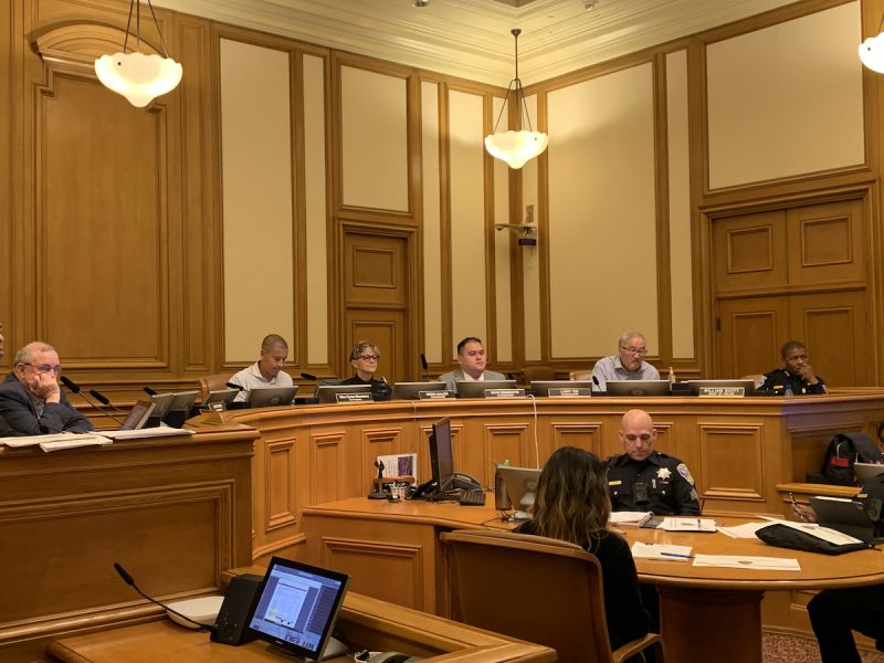 A group of people sitting at a table in a meeting hall.