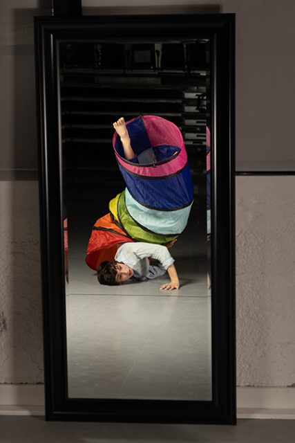 A boy lying on the floor with a colorful object in his hand.