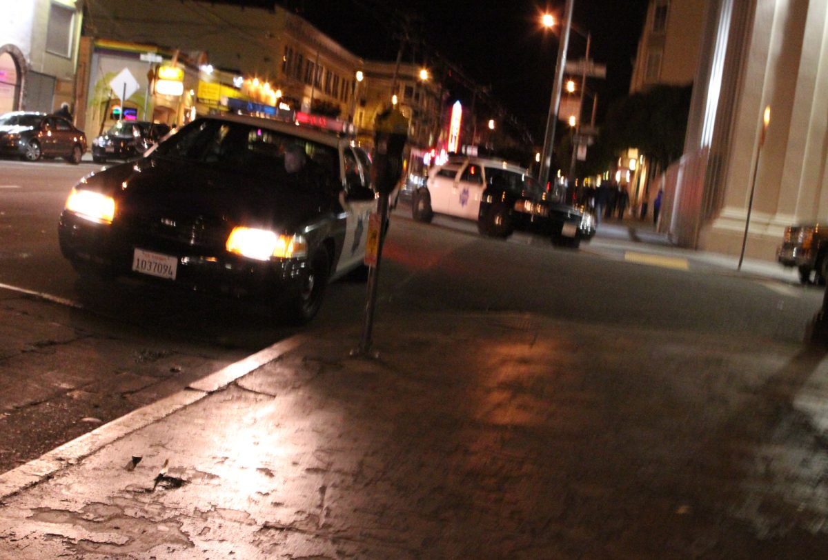 A police car driving down a city street at night.