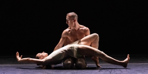 A pair of dancers on a stage in a dark room.