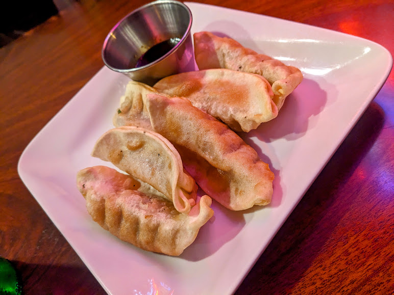 Dumplings on a plate with dipping sauce.