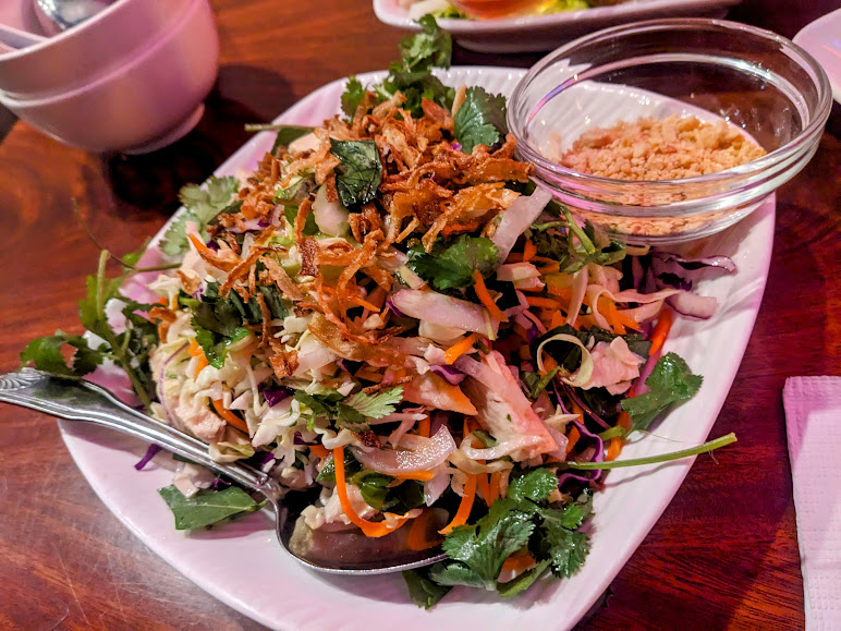 A plate of asian salad on a wooden table.