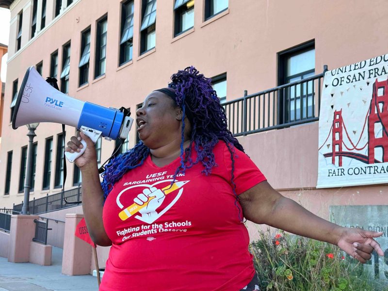 Michelle Cody holding a megaphone in front of a building.