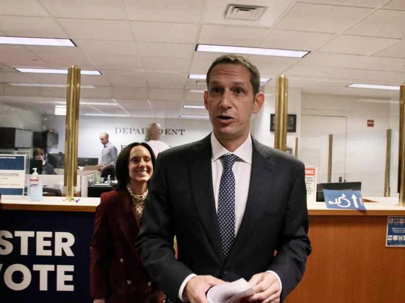 Daniel Lurie pulling papers to run for mayor, with his wife Becca Prowda standing behind him