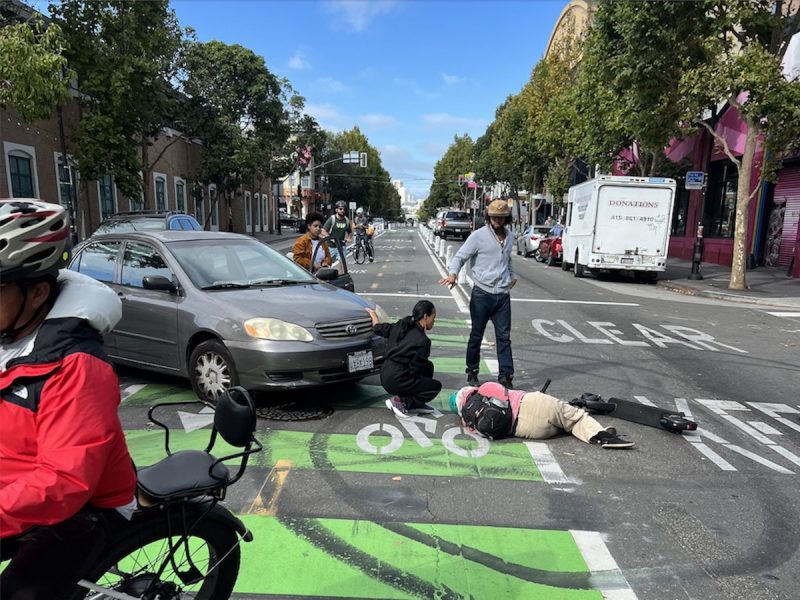 A woman is curled up in a bike lane in the middle of a street.