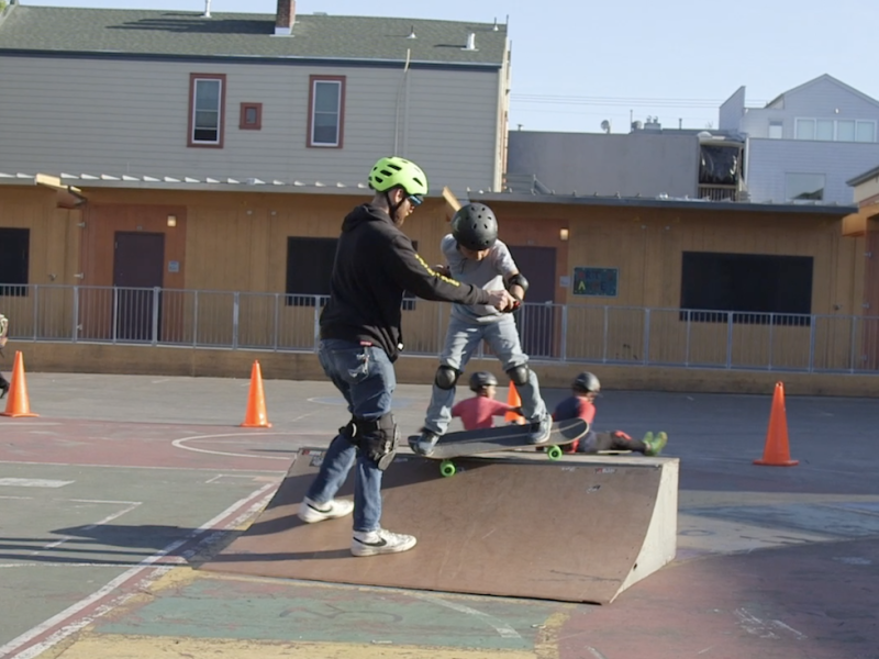 a man teaching a boy to skateboard on a ramp