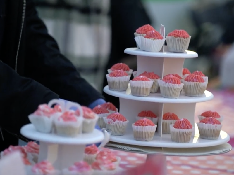 A person is holding cupcakes on a table.